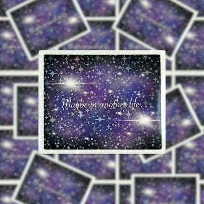 The product, "Maybe in Another Life… Holographic Sticker," showcases a captivating design with overlapping rectangular images. At the center is an image of a starry sky adorned with the phrase "Maybe in another life," highlighted by a subtle holographic sticker effect that imparts an enchanting touch.