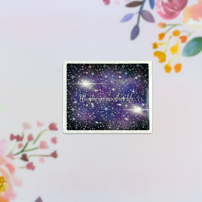 The "Maybe in Another Life... Holographic Sticker" is a rectangular decorative piece that displays a starry night sky with the phrase written in cursive. It features a pastel floral border adorned with pink, yellow, and orange flowers on a soft white background. Plus, it's dishwasher safe for your convenience.